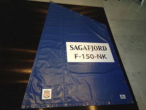 Blå trekantet presenning med teksten "SAGAFJORD F-150-NK" og maljer.